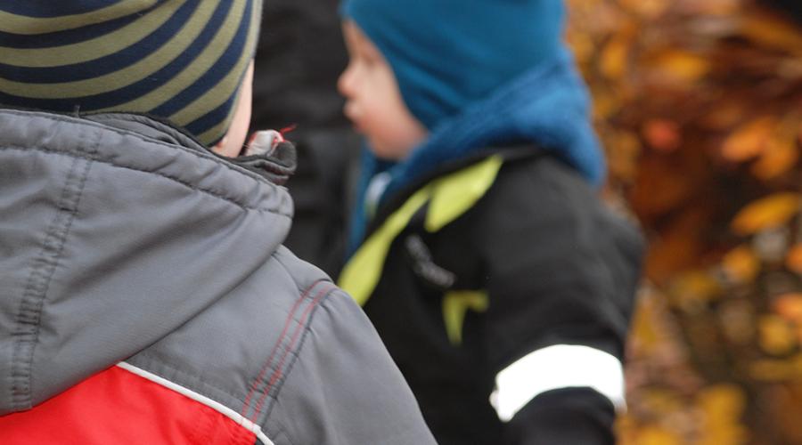 Två förskolebarn utomhus på hösten